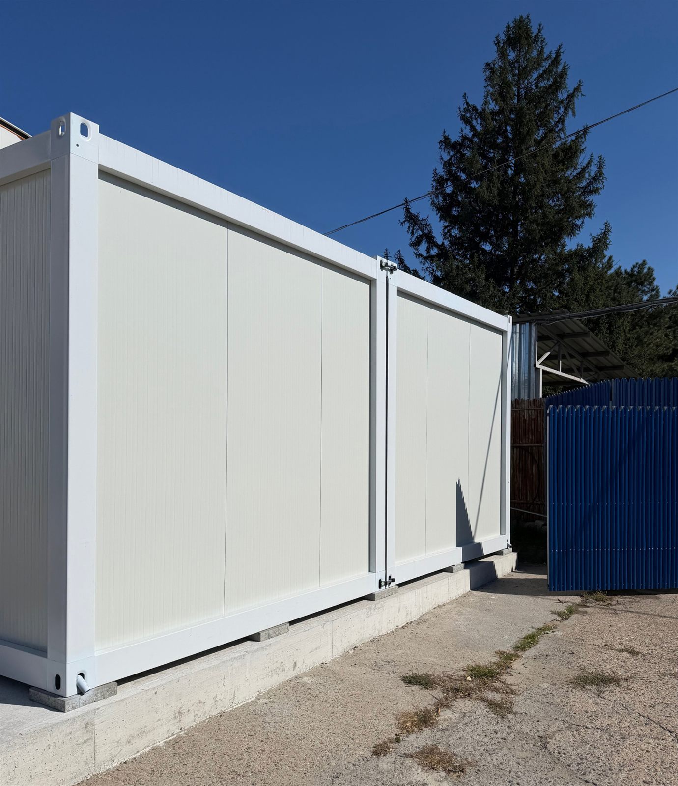 Două module albe alăturate, montate pe fundație de beton
